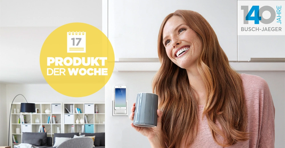 Eine lächelnde Frau hält eine Tasse in der Hand Wohnzimmer mit einem Regal im Hintergrund Auf dem Bild steht 17 PRODUKT DER WOCHE 140 Jahre BUSCH-JAEGER
