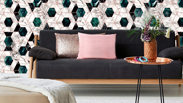 Wand mit weiß-grünen Hexagonfliesen und goldenen Fugen hinter dunkler Couch und Beistelltisch