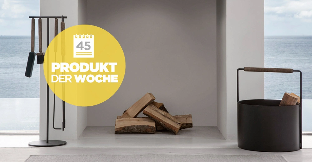 Ein Kaminbesteck steht neben einem Kamin mit Holzscheiten in einem modernen Raum mit Meerblick im Hintergrund. Gelber Kreis mit Text 45 PRODUKT DER WOCHE.