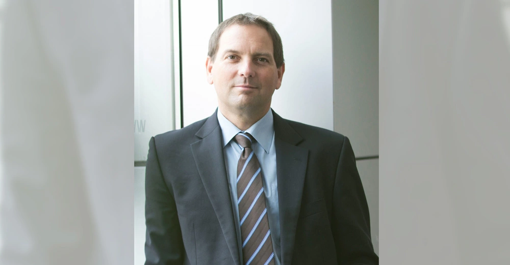 Mann trägt Anzug mit Krawatte steht gerade und blickt in die Kamera Umgebung ist ein moderner Bürogebäude-Hintergrund.