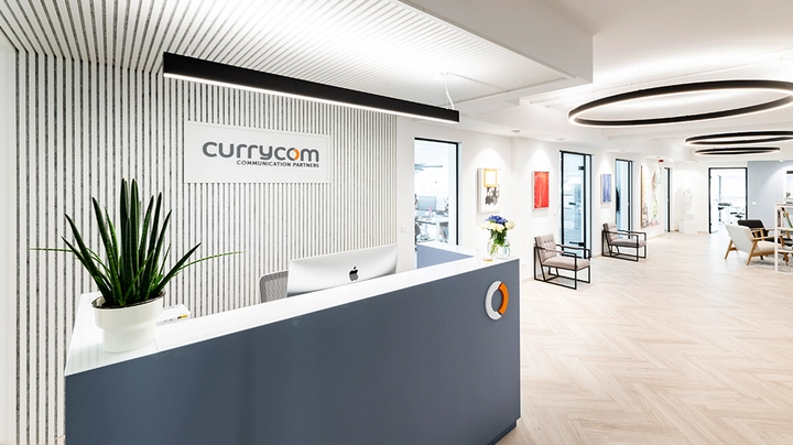 Galerie-Bild 2: Moderner Empfangsbereich der Firma Currycom mit graublauem Tresen, Pflanze und Wartezone