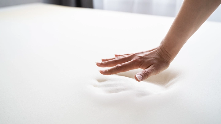 Hand schwebt über schneeweißer Memoryfoam Matratze, Handabdruck ist im Material noch gut zu sehen