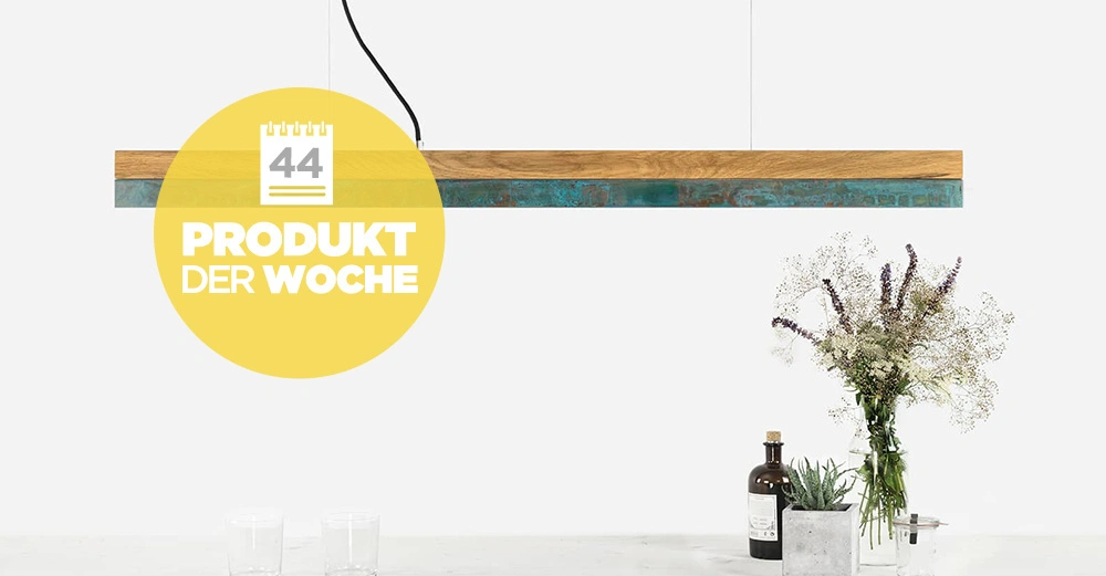 Hängelampe leuchtet über einem Tisch mit dekorativen Flaschen Gläsern und Blumen PRODUKT DER WOCHE 44 steht in einem gelben Kreis im linken Bildbereich