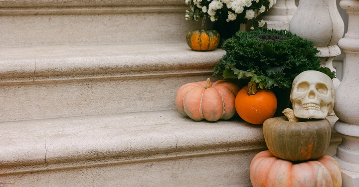 Kürbisse, Blumen und ein Schädel zur Deko für Herbst und Halloween auf den Treppen vor dem Haus.
