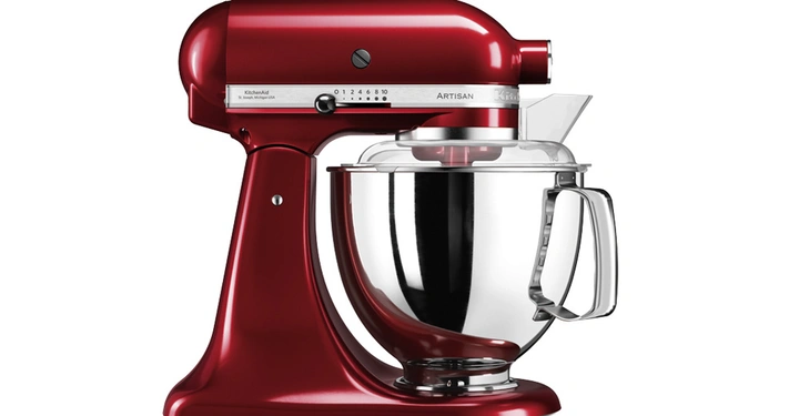 Rote Küchenmaschine steht still auf weißem Hintergrund. Sie hat eine silberne Schüssel. Text auf der Maschine: KitchenAid 5KSM185 Belgien USA Artisan 0 1 2 4 6 8 10.