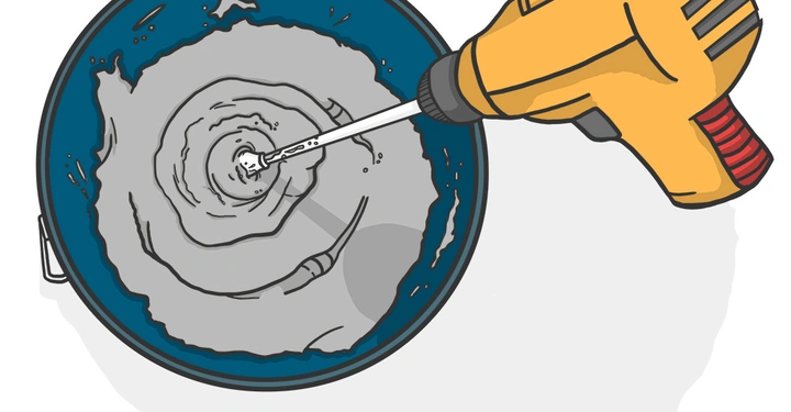 Eine gelbe Bohrmaschine mischt Beton in einem Eimer im Uhrzeigersinn.