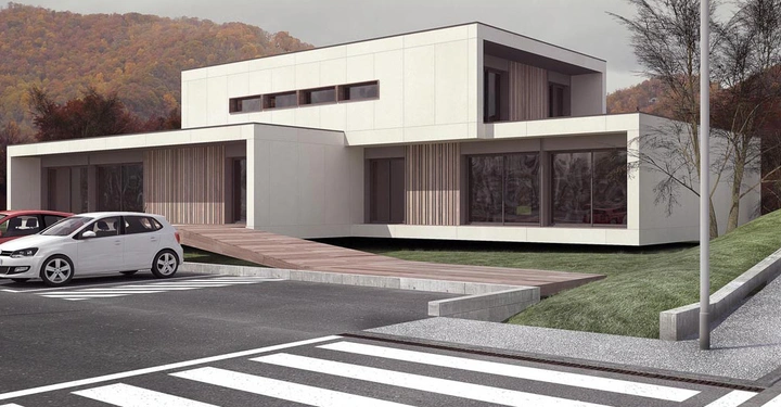 Ein weißes Auto parkt vor einem modernen weißen Gebäude mit großen Fenstern und Holzverkleidung umgeben von kahlen Bäumen und einem grünen Hügel im Hintergrund mit herbstlichen Bäumen.