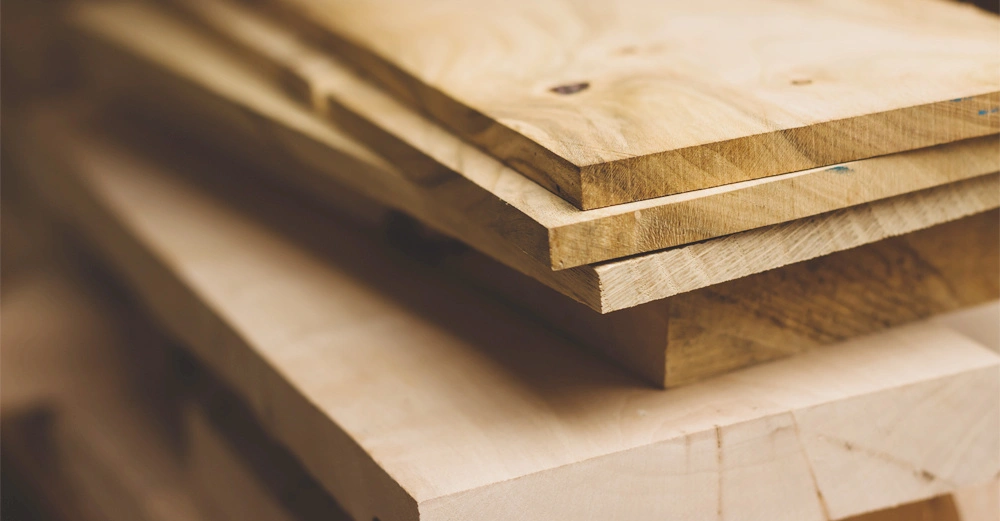 Holzbretter liegen gestapelt in einer Werkstatt und sind bereit zur Weiterverarbeitung.