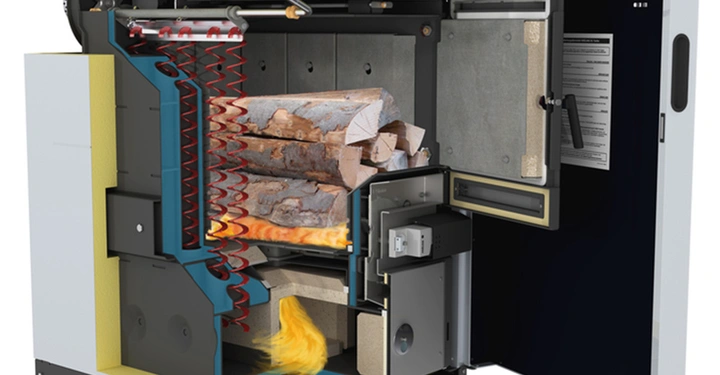 Ein Holzvergaserofen brennt Holz im Inneren ab in einer halb geöffneten Metallkammer umgeben von komplexen Rohren und einer elektronischen Anzeige in einem technischen oder industriellen Umfeld.