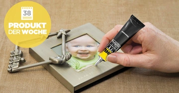 Hand trägt Kleber auf einen Bilderrahmen mit Babyfoto auf auf hellbraunem Untergrund Text: PRODUKT DER WOCHE 38