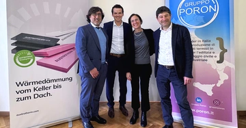 3 Männer und eine Frau stehen in Businessoutfits vor Plakaten von Austrotherm