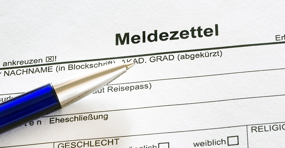 Nahaufnahme eines Stiftes und Meldezettel beim Ausfüllen, um neuen Wohnsitz anzumelden.