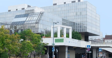 Außenansicht der Alten Wirtschaftsuniversität in Wien. Kubischer Gebäudekomplex mit Glasfassade.