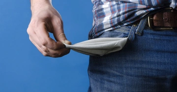 Hand zieht eine leere Hosentasche heraus Mann trägt karierte Hemd und Jeans blauer Hintergrund