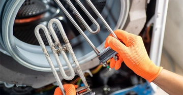 Person mit orangefarbenen Handschuhen hält zwei Heizstäbe einer Waschmaschine - einer davon ist von Kalk beschädigt, der andere neu.