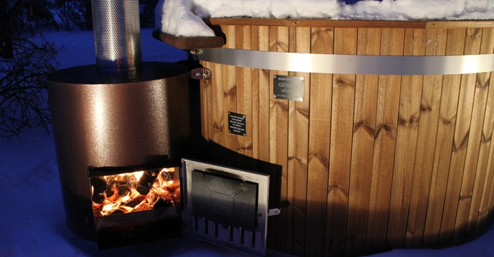 Galerie-Bild 4: Holzbeheizter Badezuber steht im Schnee Holzofen aktiv Schneebedeckter Rand umgeben von Bäumen Text: www.kirami.fi GEYS Profil 1700 L