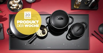 Schwarze Töpfe stehen auf einem modernen Induktionskochfeld in einer roten Küche Text: 20 PRODUKT DER WOCHE.