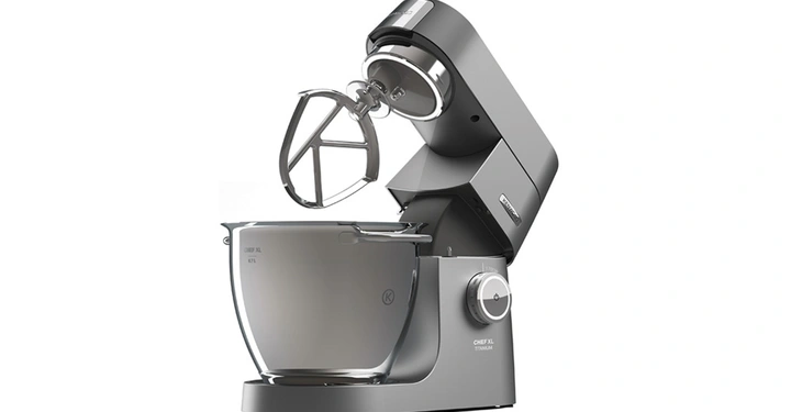 Küchenmaschine in Silber mischt in einer Edelstahl-Rührschüssel in einer modernen Wohnküche. Text auf der Maschine Chef XL Titanium.