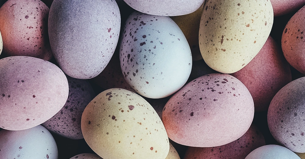 Mehrere bunte Ostereier mit Sprenkeln liegen in einem engen Haufen beieinander Eggshellfarben variieren von Pastellrosa und Gelb bis zu Blau und Lila.