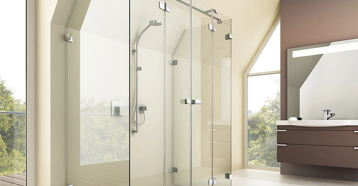 Duschkabine mit Glaswänden an einer Seite und Duschkopf Wandmontagerung im modernen Badezimmer bei Tageslicht mit großem Spiegel Waschbecken und Badmöbel vor einem Fenster mit Blick auf Bäume