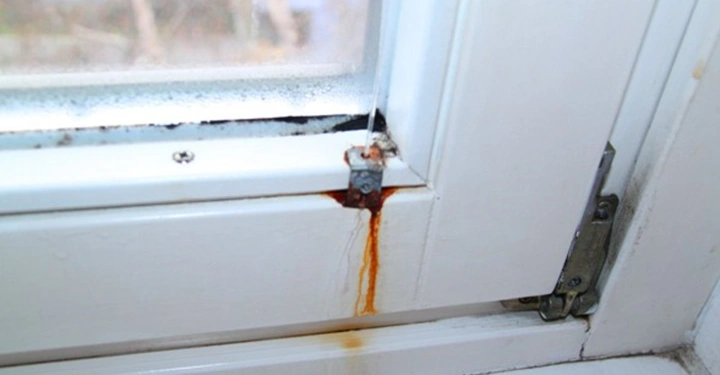 Galerie-Bild 11: Fensterecke tropft rostiges Wasser auf weißen Fensterrahmen im Innenraum mit unscharfer Außensicht im Hintergrund