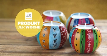 Bunte dekorative Kerzen stehen auf einem Holztisch. Im Bild gibt es einen gelben Kreis mit Text: 45 PRODUKT DER WOCHE