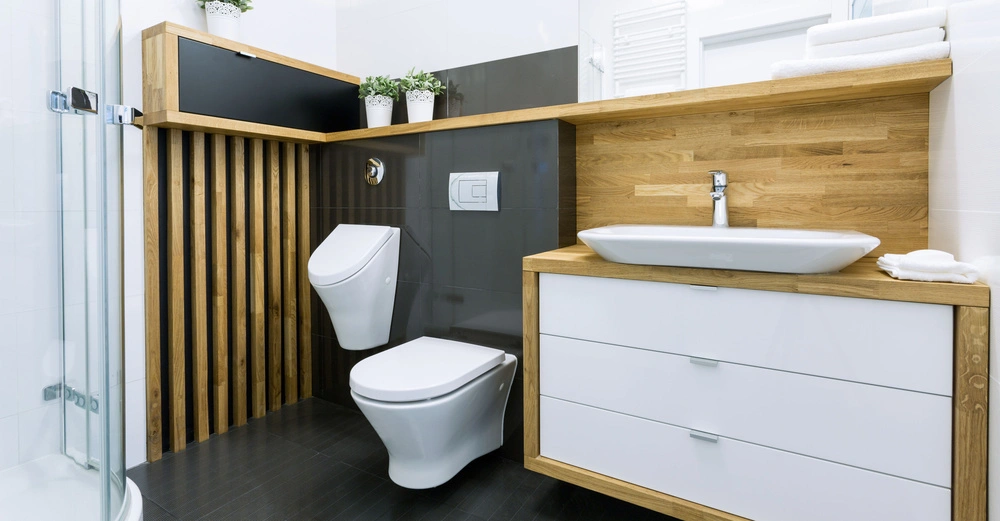 Toilette Waschbecken und Duschkabine in einem modernen Badezimmer Umfeld ist sauber und hell mit weißen Wänden Holzregalen und Pflanzen dekoriert.