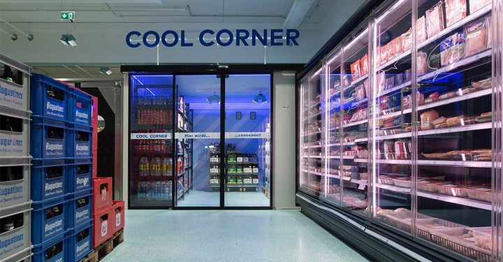 Galerie-Bild 4: Regalecke mit Getränkekisten links und einer Kühlvitrine voller Fleischprodukte rechts Ein Durchgang mit Glastüren führt zu einem Raum mit Regalen voller Getränke Text COOL CORNER Hier wirds coooooool!!