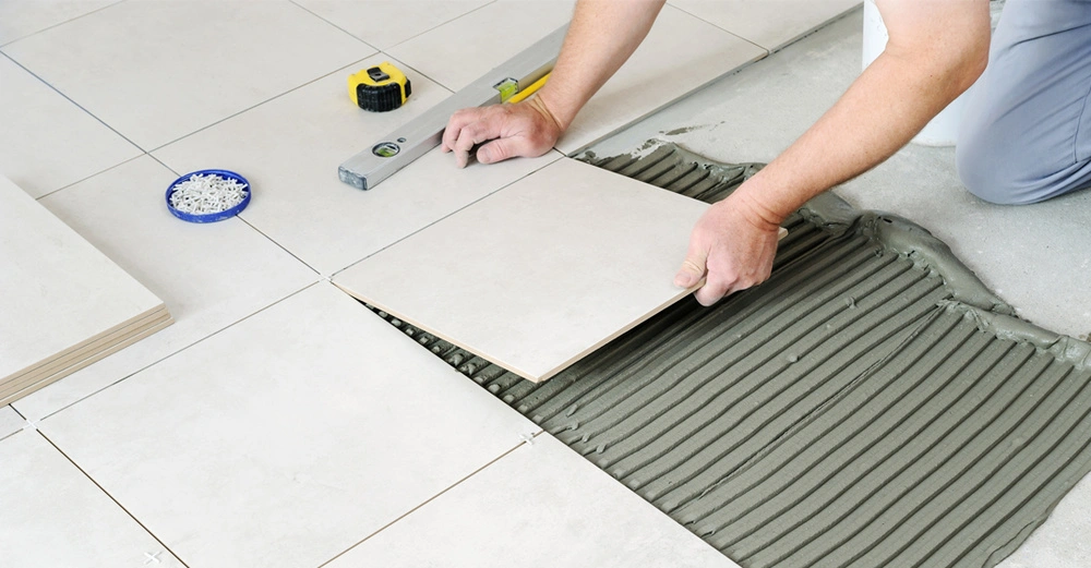 Weiße großformatige Bodenfliesen werden im Badezimmer verlegt.