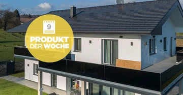 Ein modernes zweistöckiges Haus steht in einer ruhigen ländlichen Gegend neben einer Wiese. Auf dem Bild erscheint ein gelber Kreis mit dem Text 9 PRODUKT DER WOCHE.