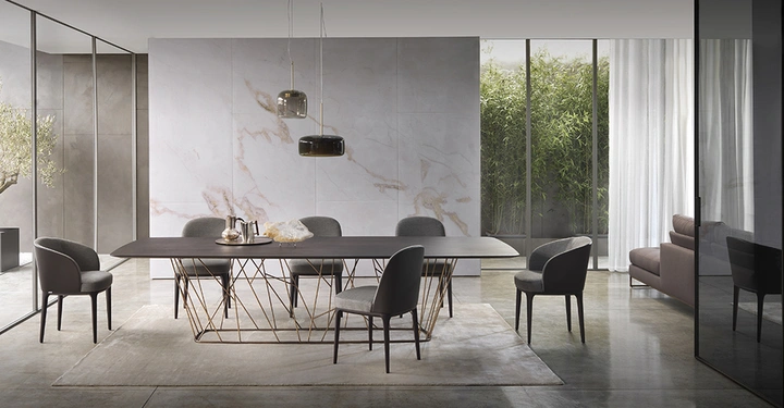 Ein großer Esstisch mit sieben Stühlen steht in einem modernen Esszimmer mit Marmorwand hinter dem Tisch und Glaswänden, die einen Garten mit Bambuspflanzen zeigen.