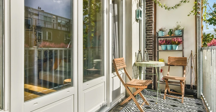 Ein schmaler Balkon, der bei der Planung optimal mit platzsparenden Klappmöbeln aus Holz und einem vintage Außenteppich gestaltet wurde.
