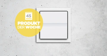 Ein weißer Lichtschalter befindet sich an einer grauen Betonwand. Ein gelber Kreis mit einem Kalender-Symbol enthält den Text 45 PRODUKT DER WOCHE.
