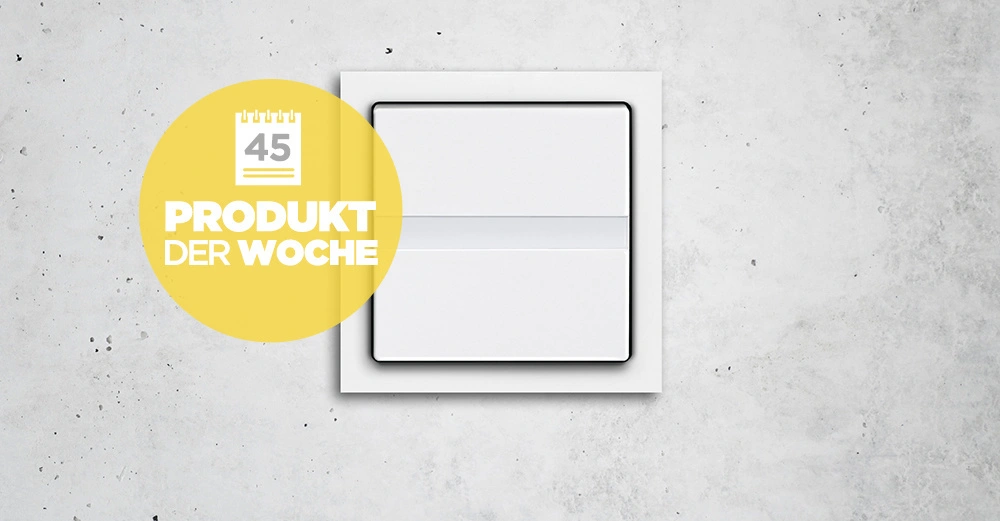 Ein weißer Lichtschalter befindet sich an einer grauen Betonwand. Ein gelber Kreis mit einem Kalender-Symbol enthält den Text 45 PRODUKT DER WOCHE.
