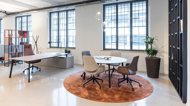 Galerie-Bild 4: Blick in großes Büro mit Schreibtisch und kleinem Besprechungstisch auf bronzefarbenem Teppich