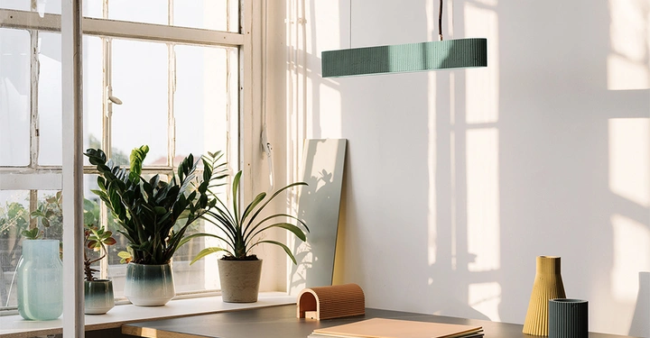 Pflanzen stehen auf einem Tisch neben einem großen Fenster Sonnenlicht durchflutet den Raum Modernistischer Kronleuchter hängt von der Decke Diverse Vasen und Wohnaccessoires ergänzen die helle Einrichtung