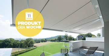 Sonnenschutzvorrichtung aus Stoff über einer modernen Terrasse mit Glasgeländer, grüne Wiesen und bewaldete Hügel im Hintergrund. Text im Bild: 11 PRODUKT DER WOCHE