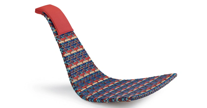 Ein bunter gewebter Schaukelstuhl mit einem roten Kissen ruht auf einer weißen Fläche.