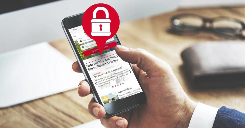 Eine Hand hält ein Smartphone welches eine Nachrichten-Website zeigt. Ein rotes Schloss-Symbol über dem Bildschirm deutet auf Sicherheit hin. Im Hintergrund ein Schreibtisch mit Brille und Notizbuch.