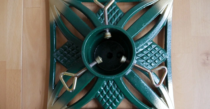 Quadratischer Christbaumständer aus Metall in Grün und Gold mit klassischen Schraubzwingen von oben gesehen.