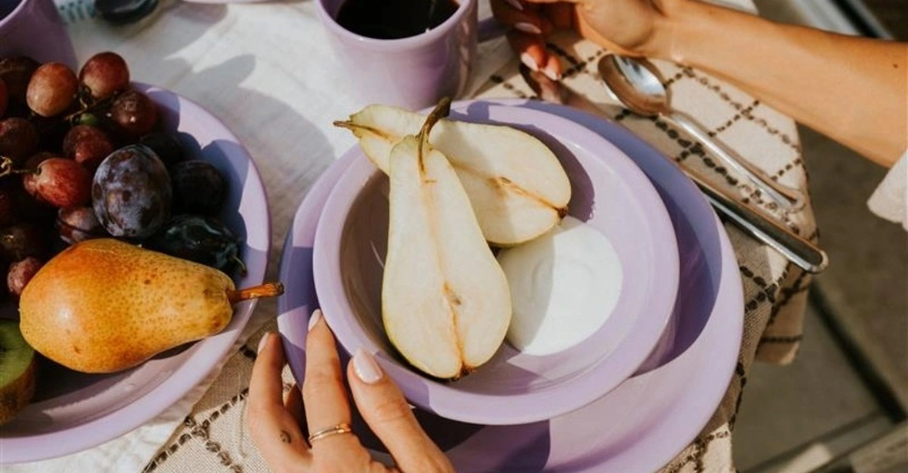 Nahaufnahme eines sonnigen Frühstückstischs mit Keramik in Flieder von Gmundner Keramik.