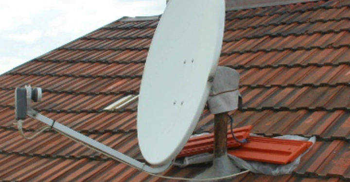 Galerie-Bild 24: Satellitenschüssel befestigt an einem geneigten roten Ziegeldach in einer städtischen Umgebung an einem bewölkten Tag