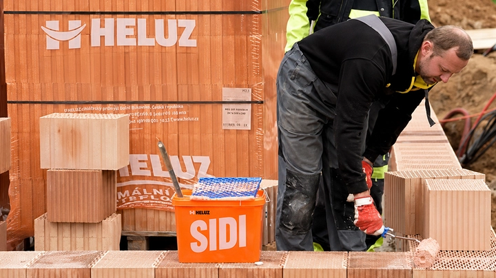 Galerie-Bild 1: Bauarbeiter verarbeitet HELUZ SIDI Dünnbettmörtel beim Errichten einer Ziegelwand aus HELUZ-Ziegeln auf einer Baustelle.