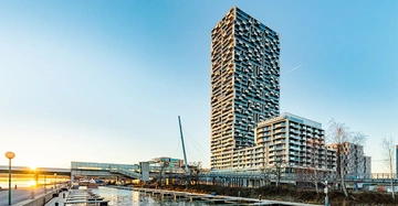 Hochhaus steht still im modernen Hafengebiet neben einem Kanal bei Sonnenuntergang Wohnungen und Gebäude in der Umgebung