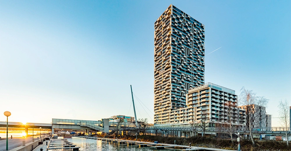 Hochhaus steht still im modernen Hafengebiet neben einem Kanal bei Sonnenuntergang Wohnungen und Gebäude in der Umgebung