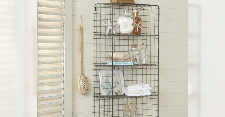 Galerie-Bild 3: Drahtregal hält Gläser Handtücher und Badezimmerutensilien montiert an einer hellen Holzwand mit Haken und einer Bürste daneben. Links sind Lamellenfenster.