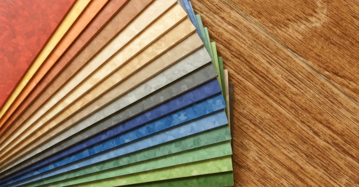 Mehrfarbige Stoffmuster liegen fächerförmig angeordnet auf hellem Holzfußboden