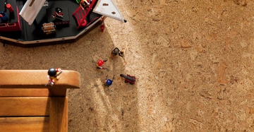 Holzschiff sitzt auf einem Korkboden Piratenfiguren führen Aktivitäten um und auf dem Schiff aus linker Hintergrundteil eines Holzstuhls.