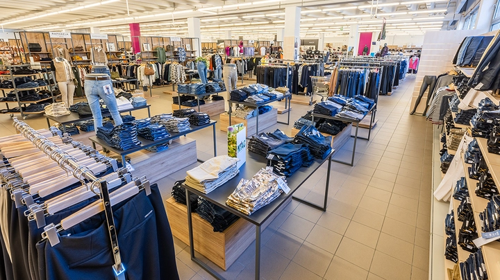 Galerie-Bild 3: Großzügige Modefläche mit Jeans, Hosen und gefalteter Kleidung auf Tischen in der Astro Filiale Wiener Neustadt