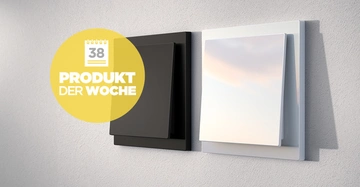 Zwei Lichtschalter in Schwarz und Weiß an einer grauen Wand Kontext ein gelber Kreis mit der Aufschrift 38 PRODUKT DER WOCHE.